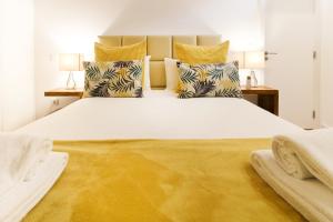 Un dormitorio con una gran cama blanca con almohadas amarillas. en MSC Flats - Comercio do Porto, en Oporto