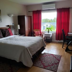 a bedroom with a bed and a window with red curtains at Antigonish Evergreen Inn in Antigonish