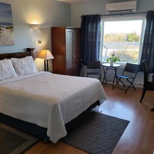 a bedroom with a bed and a table and a window at Antigonish Evergreen Inn in Antigonish