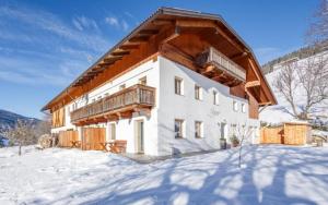 a house with a wooden roof in the snow at Agriturismo MARER Urlaub auf dem Bauernhof in Villabassa