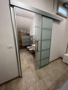 een badkamer met een glazen deur en een badkamer met toilet bij B&B Quintadecima in Uggiano la Chiesa