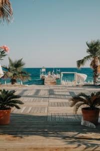 a wooden boardwalk leading to the ocean with palm trees at RAW BEACH HOTEL in Antalya