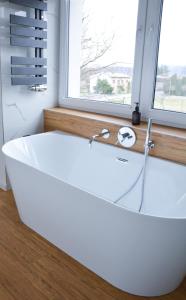 La salle de bains est pourvue d'une baignoire blanche et d'une fenêtre. dans l'établissement Luxury apartment with private sauna Pod Javorovým, à Třinec