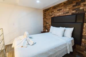 a bedroom with a white bed with a brick wall at Hotel Revolución in Tijuana