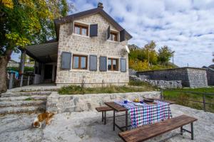 a small stone house with a table and a dog at Guest House Lovcen in Cetinje