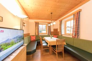 a dining room with a table and a television at Gästehaus Müllauer in Leogang