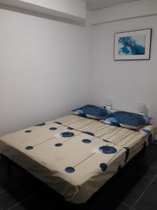 un grande letto con cuscini blu in una camera da letto di 3soleils a Schœlcher