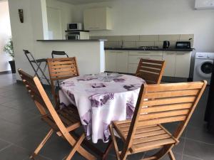 a dining room table with three chairs and a kitchen at 3soleils in Schœlcher