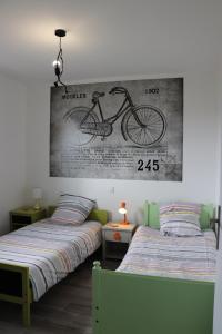 1 dormitorio con 2 camas y un dibujo de una bicicleta en la pared en gîte la bêcyclette de la baie de Somme, en Mons-Boubert