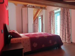 uma cama vermelha num quarto com uma janela em Casa Vacanza Lo Nânò em Fenis