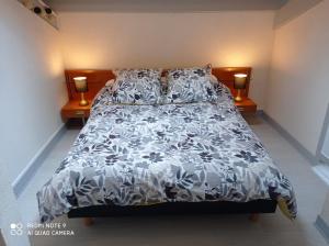 a bedroom with a bed with a black and white comforter at Gîte A-B Roger in Ganties