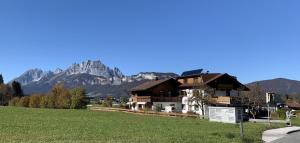 ein Haus auf einem Feld mit Bergen im Hintergrund in der Unterkunft Ferienwohnungen Pletzenauer in Sankt Johann in Tirol