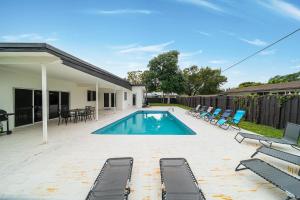 ein Swimmingpool mit Liegestühlen und ein Haus in der Unterkunft Pool Villa in Miami