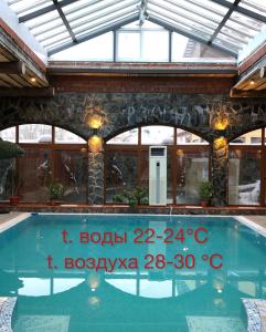 a swimming pool in a house with a glass roof at Guest House Valeria in Velikiy Novgorod