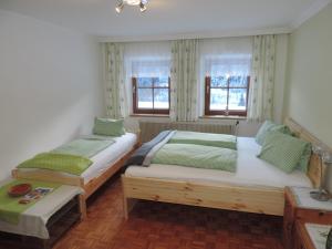 dwa łóżka w pokoju z dwoma oknami w obiekcie Unterlanschützhof w mieście Sankt Michael im Lungau