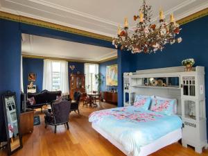 a bedroom with blue walls and a bed and a chandelier at Villa Dalenstein in Velp