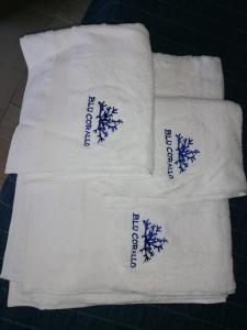 um grupo de toalhas brancas com escrita azul nelas em Blu Corallo Villa em Alcamo