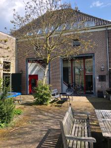 a bench in front of a brick building with a tree at Monumental villa at the forest close to Haarlem and the beach in Heemstede