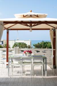uma mesa e cadeiras sob um guarda-sol num pátio em Blu Corallo Villa em Alcamo