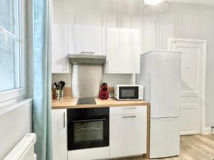 a kitchen with white cabinets and a microwave at Arina & Julien Dieppe in Dieppe