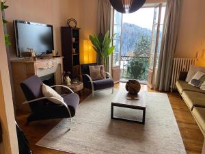 uma sala de estar com um sofá e cadeiras e uma televisão em Ancient Hotel Mont Joly - 3 bedr - view - 2 bath - 80m2 em Saint-Gervais-les-Bains