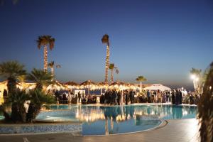a group of people standing around a pool with palm trees at MOOD Sea Stage in Castiglione