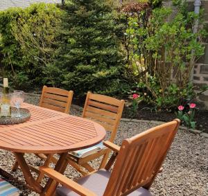 a wooden table with three chairs and a table with glasses on it at Westwood Cottage in Dundee