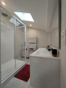 La salle de bains blanche est pourvue d'une douche et d'un lavabo. dans l'établissement Bon encontre, Allée de la vierge, à Bon-Encontre