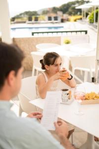 una mujer sentada en una mesa bebiendo una copa de vino en Hotel Piramide, en Portonovo