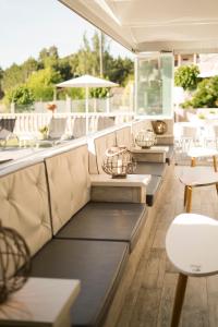 eine Reihe von Bänken auf einer Terrasse mit Tischen und Stühlen in der Unterkunft Hotel Piramide in Portonovo