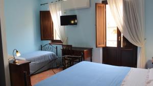 1 dormitorio con 2 camas, escritorio y ventana en B&B Mela, en Rogiano Gravina