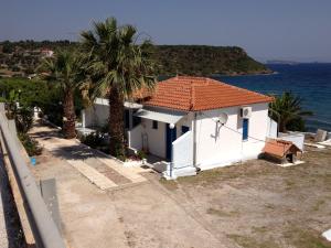 a white house with palm trees next to the ocean at George Paradise in Nees Kidonies