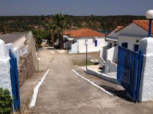 una strada con case bianche e una recinzione blu di George Paradise a Nees Kidonies