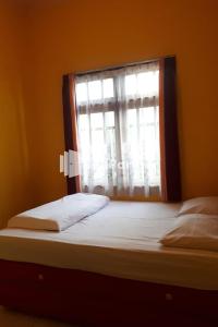 1 dormitorio con 1 cama y una ventana con sábanas blancas en Bromo Indah Lestari Homestay Mitra RedDoorz, en Pasuruan
