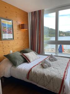Schlafzimmer mit einem großen Bett und einem Fenster in der Unterkunft Appart'Hôtel LIDO au bord de l'eau in Gérardmer