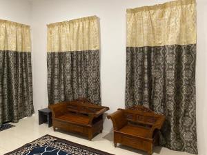 a living room with two chairs and curtains at An-Nur Homestay in Sungai Petani