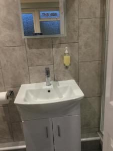 ein Badezimmer mit einem weißen Waschbecken und einem Spiegel in der Unterkunft The Hide at Pinchbeck in Spalding