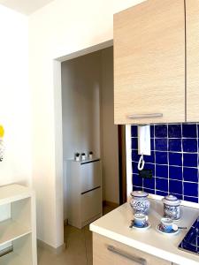 a kitchen with a white counter and a blue tile wall at Casa Serra in Porto Palo