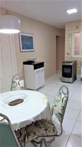 een keuken met een tafel en stoelen en een fornuis bij Casa a uma quadra da praia in Maresias