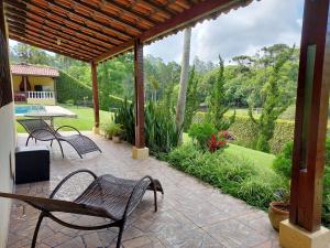 a patio with chairs and a table and a garden at Chácara do Darcio SP in Itapecerica da Serra