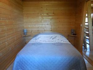 ein Schlafzimmer mit einem Bett in einem Holzzimmer in der Unterkunft Le chalet bois de Célio in Coux