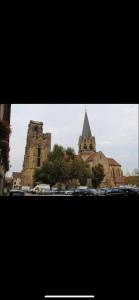 a church with a steeple and cars parked in front of it at Chez Ben et Maé in Rouffach