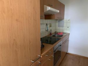 una pequeña cocina con armarios de madera y fregadero en BodenSEE Apartment Wasserburg Sonnhaldenstraße, en Wasserburg