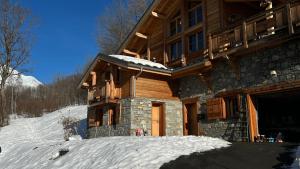 uma cabana de madeira com neve no chão à sua frente em mini duplex dans chalet em Saint-François-Longchamp