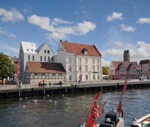 eine Gruppe von Booten im Wasser vor Gebäuden in der Unterkunft Hotel New Orleans in Wismar