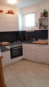 cocina con armarios blancos, fregadero y ventana en Trento- Monte Bondone Appartamento tipico di montagna en Norge