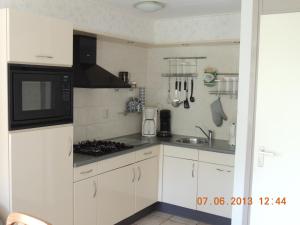 a kitchen with white cabinets and a black microwave at Vinkie in De Waal +5 photos