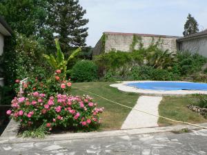 um jardim com flores cor-de-rosa e uma piscina em la Maison d'Arbouet 