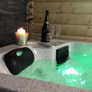 a hot tub with a bottle of wine and glasses at La VILLA en BAIE in Le Crotoy