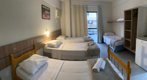 a room with three beds and a window at Pousada Bella Nina in Balneário Camboriú